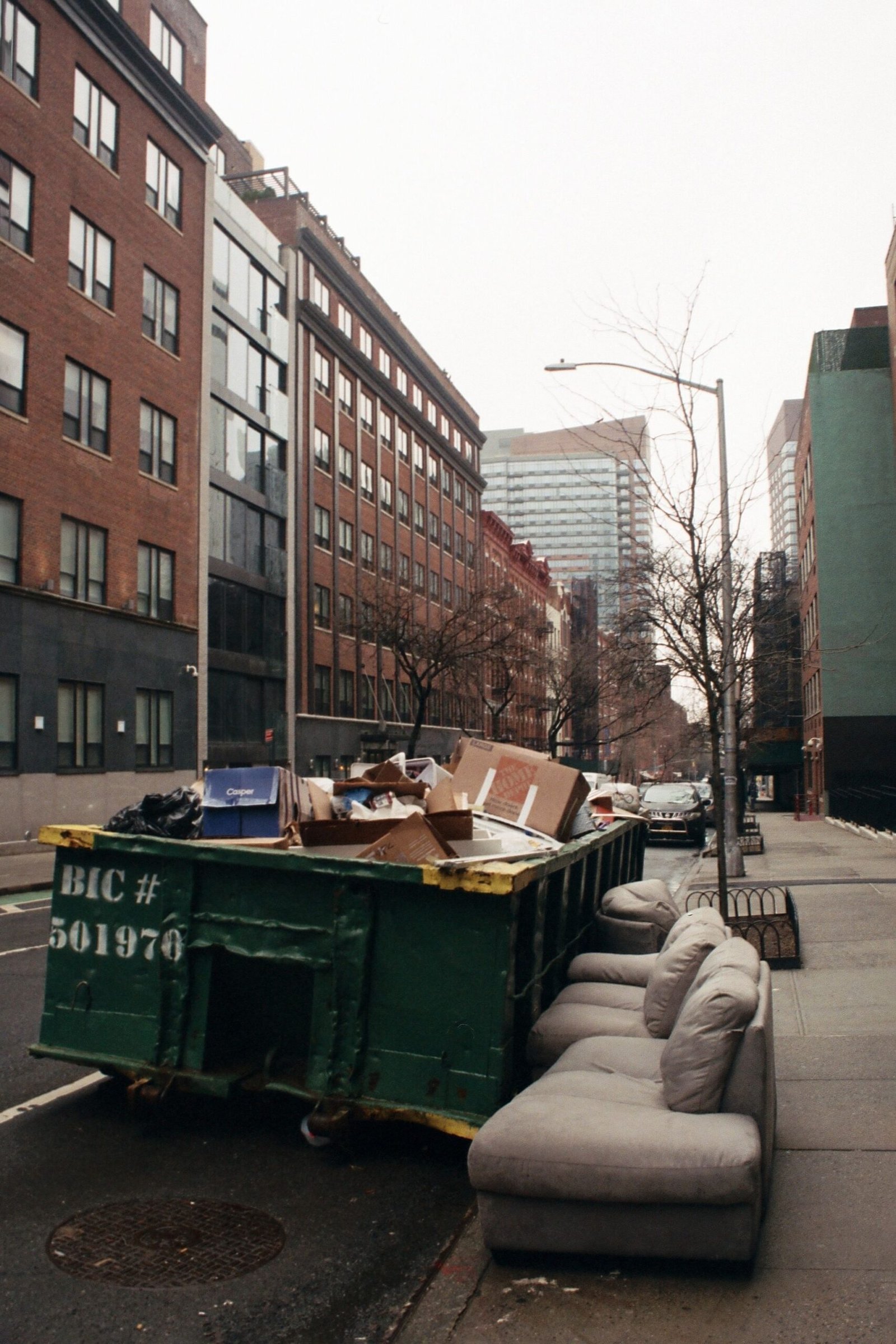 City street with buildings, trash, and discarded furniture.